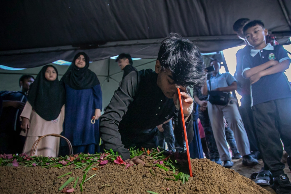 Zhakil Iman Khairil Azhar, 18, the second son of the late Inspector Khairil Azhar Kamaruddin, fights back tears at his father’s grave after the burial at the Tanjung Rambutan Masjid Jamek Islamic Cemetery in Ipoh January 23, 2026. — Bernama pic