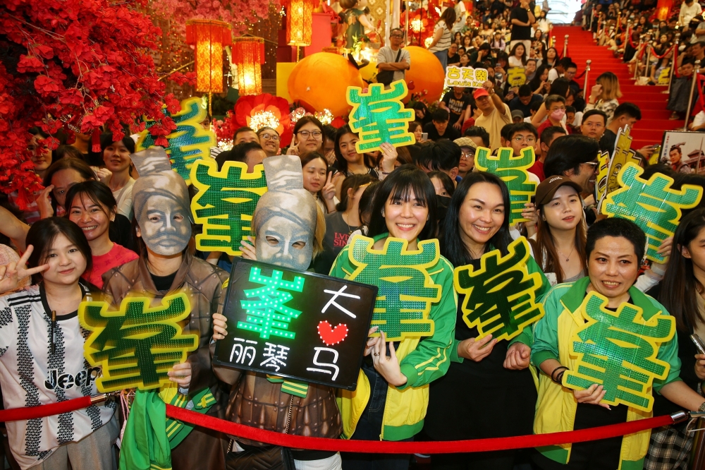 Fans in the front row showcase signs for Raymond Lam, the actor who brought the character Chiu Poon to life. — Picture by Choo Choy May