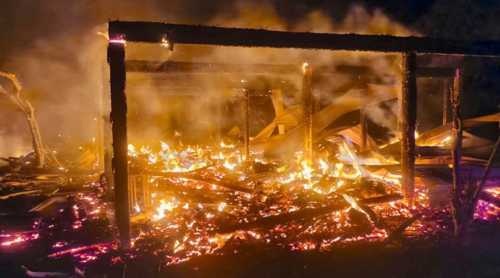 Flames engulf what is left of a home in Kampung Lausan, Kudat, where a couple were found dead in their bedroom. — Picture via Facebook