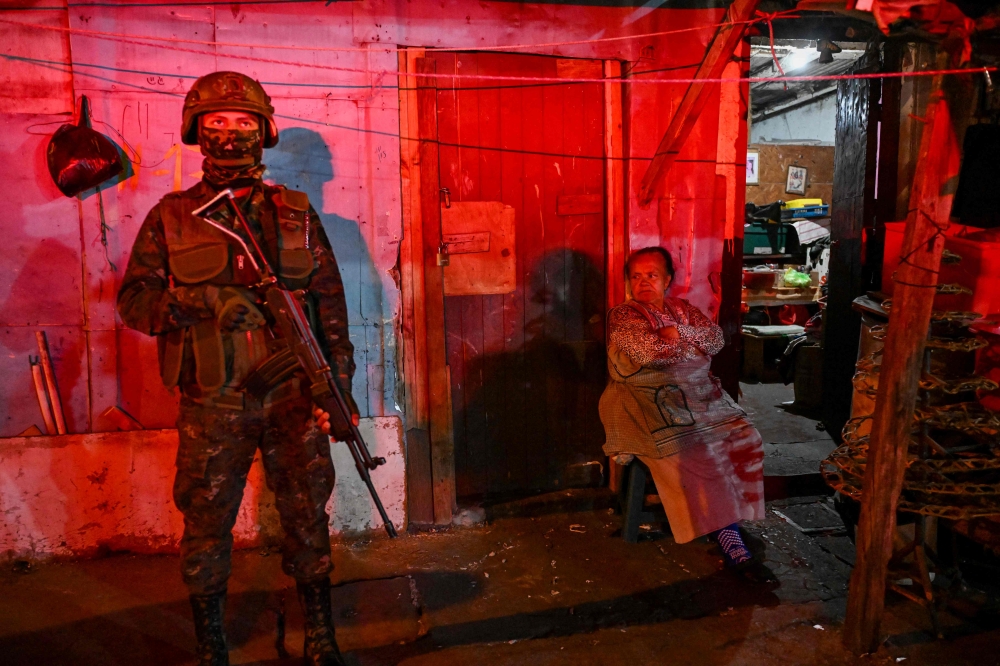 A Guatemalan Army soldier stands guard next to an elderly woman on a street of the Gallito neighborhood during the state of emergency declared by the government in Guatemala City on January 22, 2026. Guatemalan soldiers began patrolling gang-controlled neighborhoods in the capital on January 20, after attacks that left ten police officers dead and prompted the government to declare a state of siege, according to official sources and an AFP journalist. — AFP pic