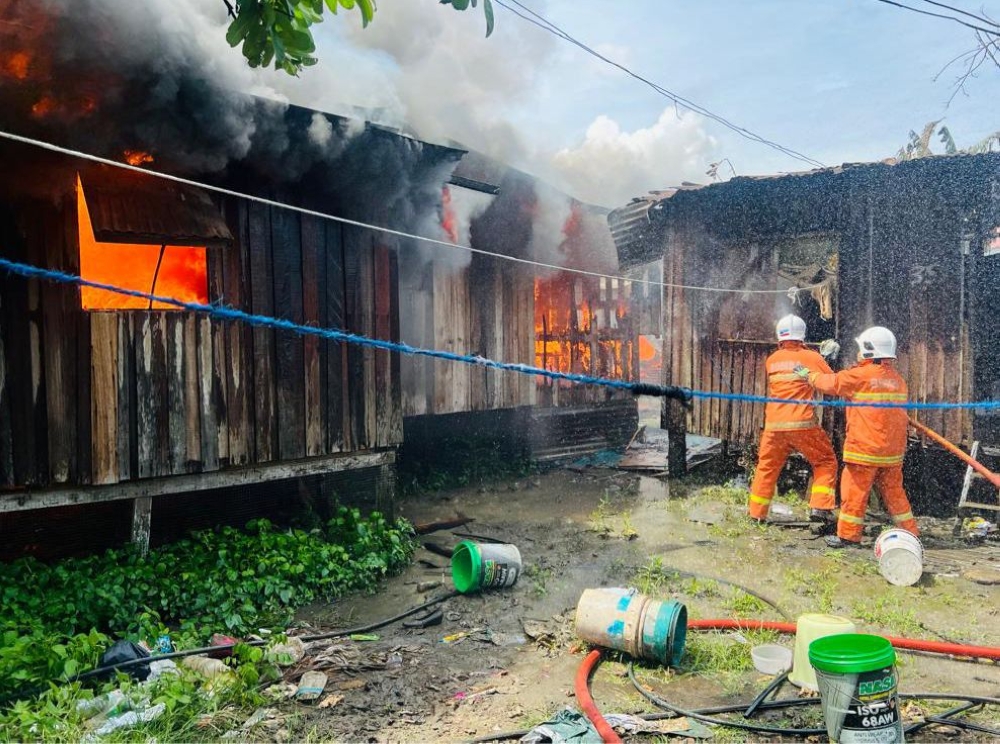 Bomba personnel attempting to put out the fire which killed a woman and destroyed seven squatter houses at Kampung Pirigi in Semporna. — Picture courtesy of Fire and Rescue Department