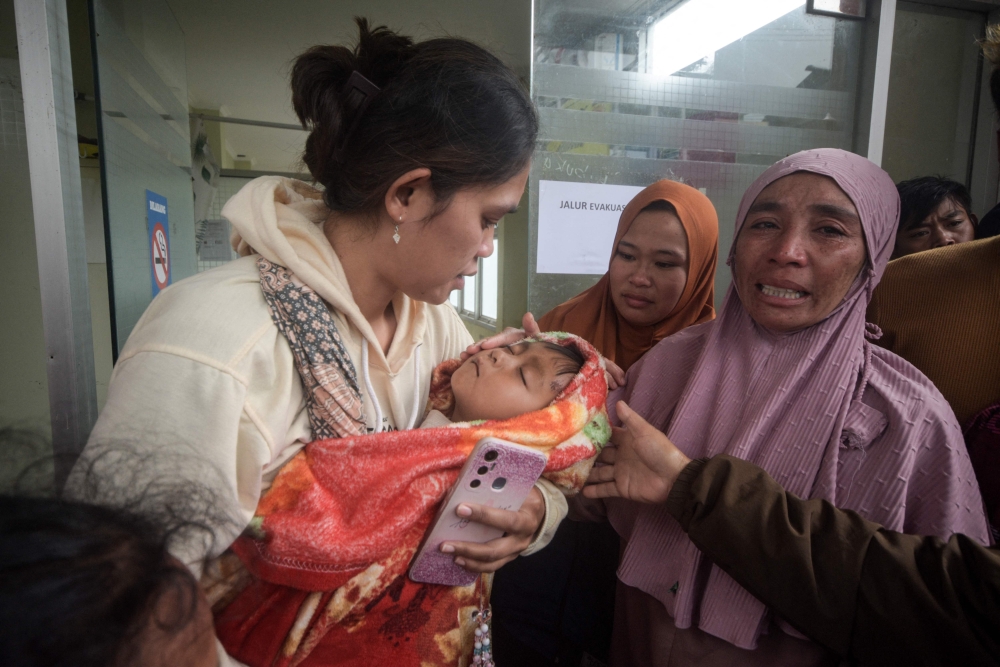 A woman caries a boy who survive a landslide at Pasirlangu village in Bandung, West Java, Indonesia on January 24, 2026. — AFP pic