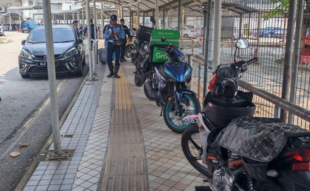 Kuala Lumpur City Hall (DBKL) enforcers approach motorcycles parked illegally on a pedestrian walkway in Brickfields. — DBKL pic