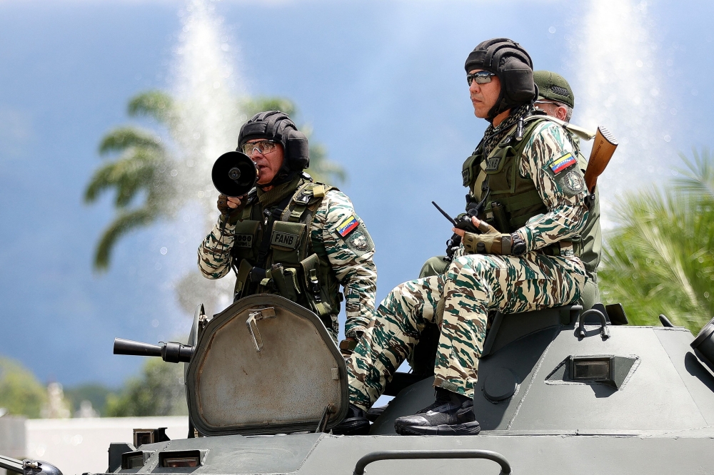 Venezuela's Defence Minister Vladimir Padrino Lopez (left) speaks with a loudspeaker on a Venezuelan army tank after a military exercise, at a highway in Caracas on September 20, 2025. — AFP pic