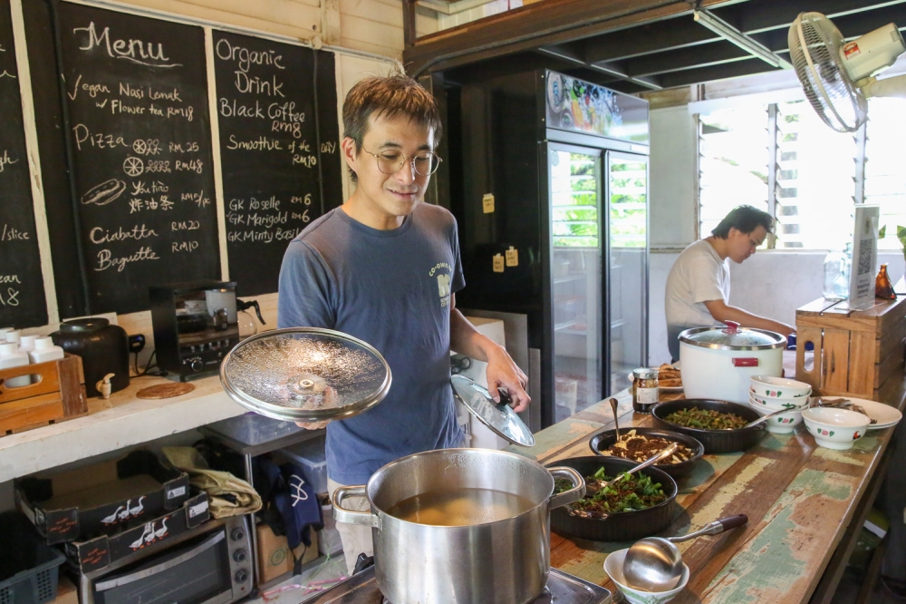 Kongsi Co-op partner Lau Jia Hao shares insights on farm-to-table food while working behind the counter at the pop-up cafe at Kongsi House. — Picture by Choo Choy May