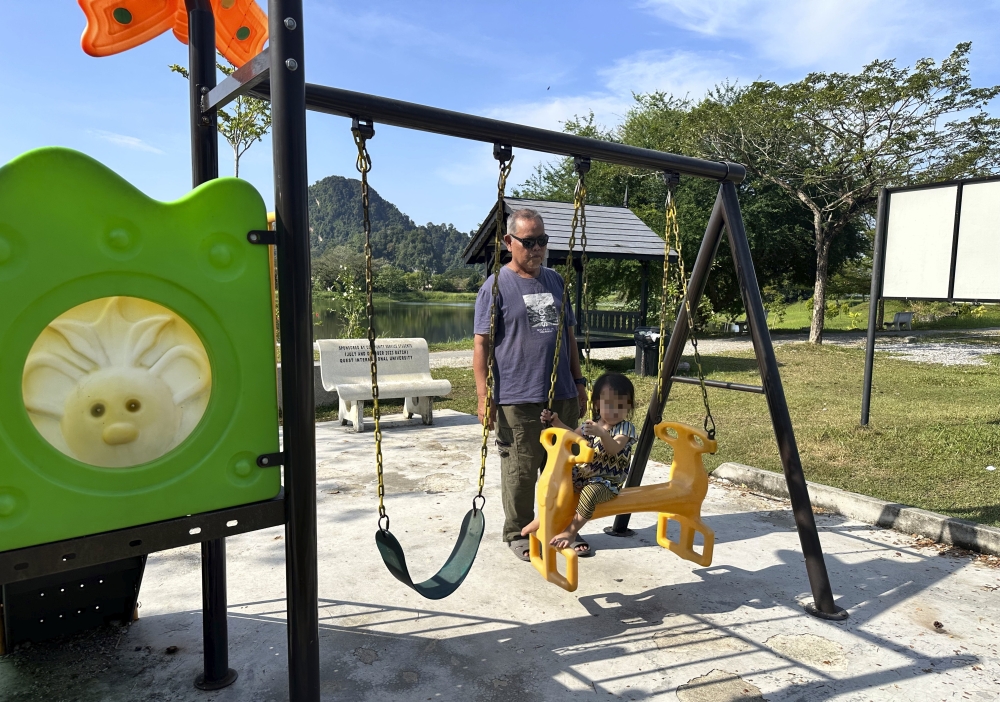 Grandfather Ahmad Ramli Razali, 64, keeps a close eye as his granddaughter plays. — Bernama pic