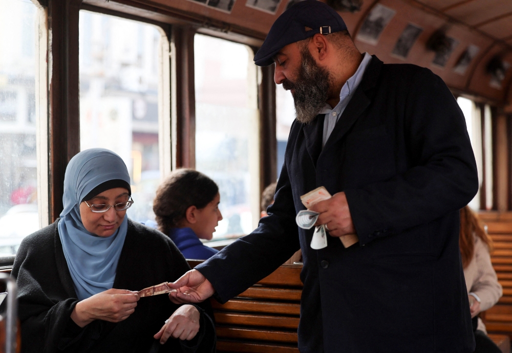 A woman buys a ticket from tram conductor Negm El-Din Talaat, January 25, 2026. — Reuters pic