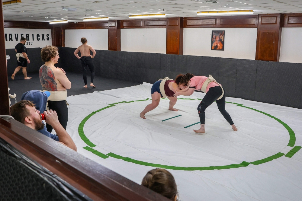 Sumo wrestlers Tori Moffett (centre left) and Toraigh Mallon (right) practising in the ring during a sumo wrestling training session at a club in Belfast, Northern Ireland. — AFP pic