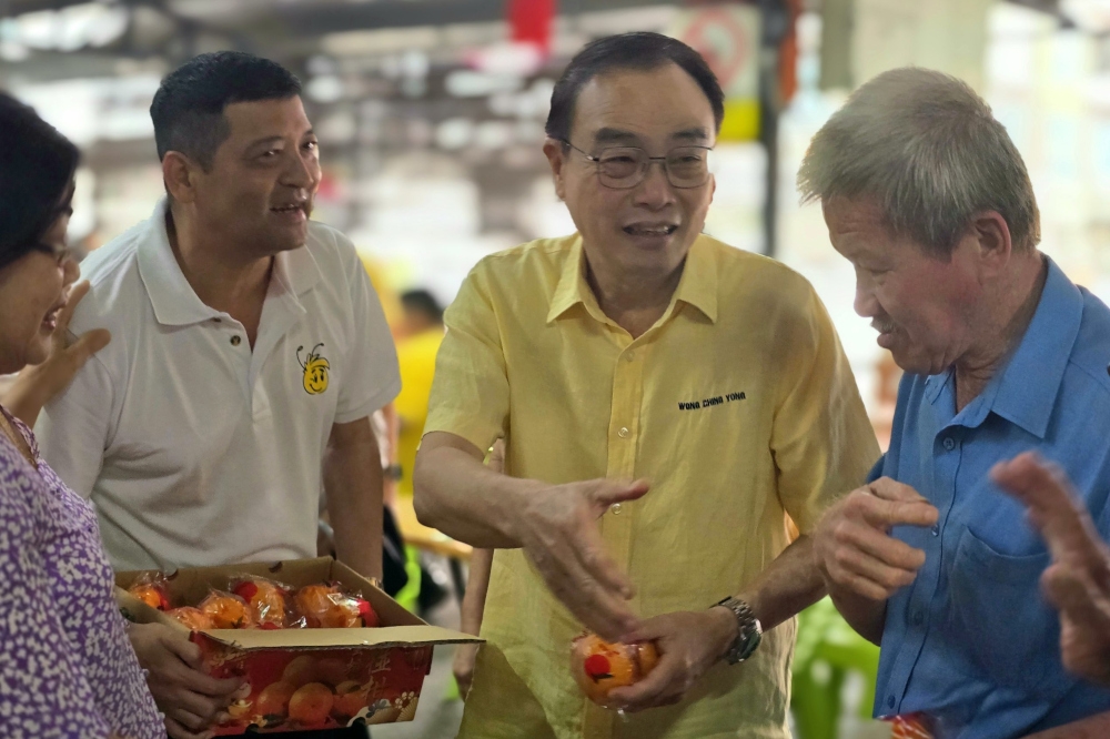 Sarawak United People’s Party (SUPP) Dudong chairman Wong Ching Yong extends Lunar New Year greetings to hawkers during the mandarin orange distribution event. — The Borneo Post pic 