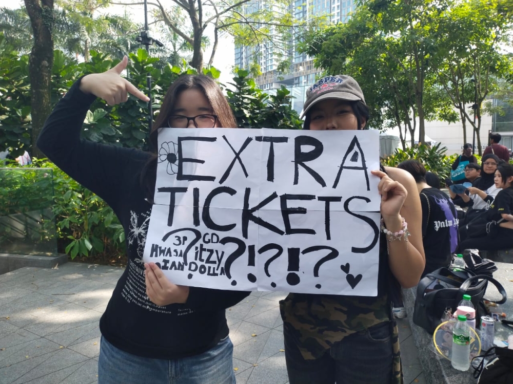 Two fans wait at Stadium Merdeka ahead of the K-Spark event, hoping to get a discounted or free ticket. — Picture by Ian Jeremiah Patrick
