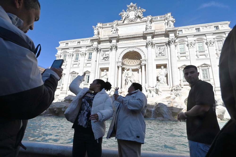 Visitors throw coins into the Trevi Fountain in Rome after the city introduces a two-euro paid entry, on February 2, 2026. — AFP pic