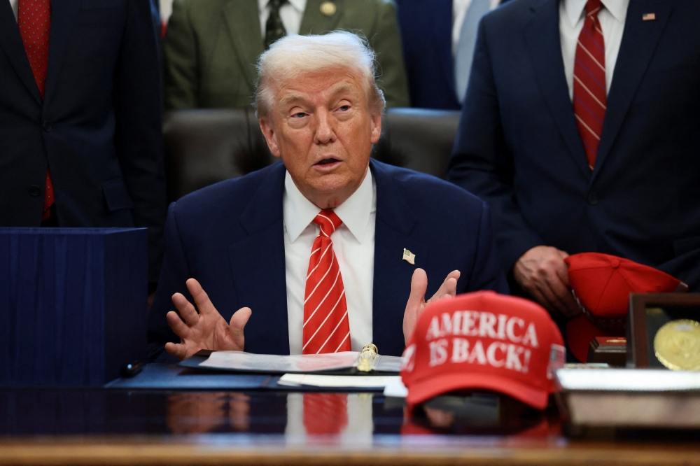 US President Donald Trump sits at his desk, behind a hat that reads ‘America is back’ at the White House in Washington February 3, 2026. — Reuters pic