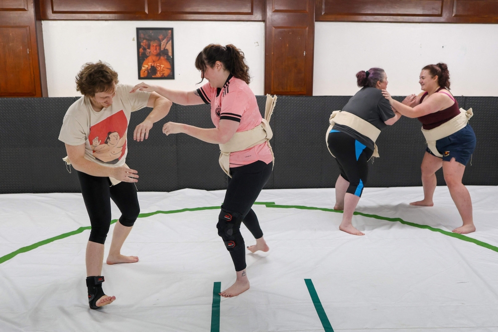 This photo taken on January 16, 2026 shows Johnny Templeton (left), the sumo wrestling club founder and coach, taking part in a training session with wrestler Toraigh Mallon (second left) at the club in Belfast, Northern Ireland. Sumo's origins can be traced back some 2,000 years and rituals like purification, bowing and ring-entering ceremonies are woven into competition. Now the sport's roots are spreading with clubs sprouting in Dublin, Cork, and rural Northern Ireland as interest grows. — AFP pic