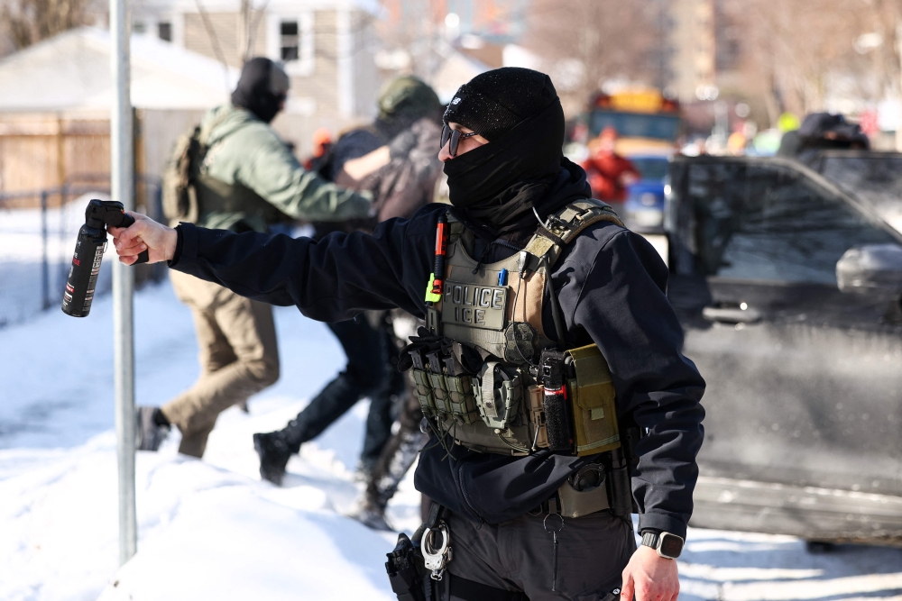 A federal agent holds up a bottle of irritant as other agents detain a protester in Minneapolis, Minnesota on February 3, 2026. — AFP pic