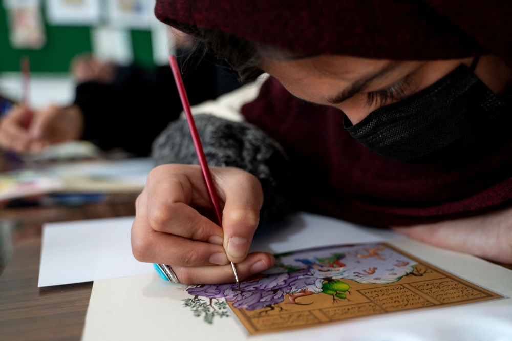 This picture taken on January 7, 2026 shows an Afghan woman painting miniature art at a workshop in Herat. — AFP pic
