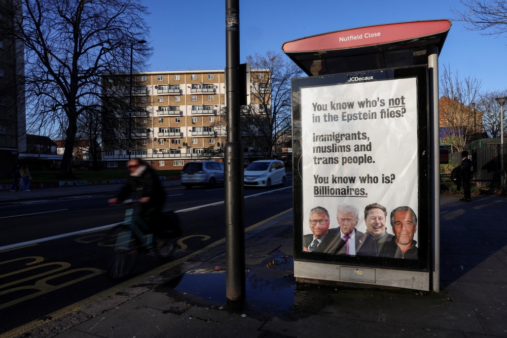 A cyclist rides past a poster installed on a bus stop by campaign group Everyone Hates Elon featuring entrepreneur Elon Musk, the late financier and convicted sex offender Jeffrey Epstein, US President Donald Trump and American businessman and philanthropist Bill Gates, all of whom have appeared in newly released Epstein‑related files, in London, Britain, February 4, 2026. — Reuters pic 
