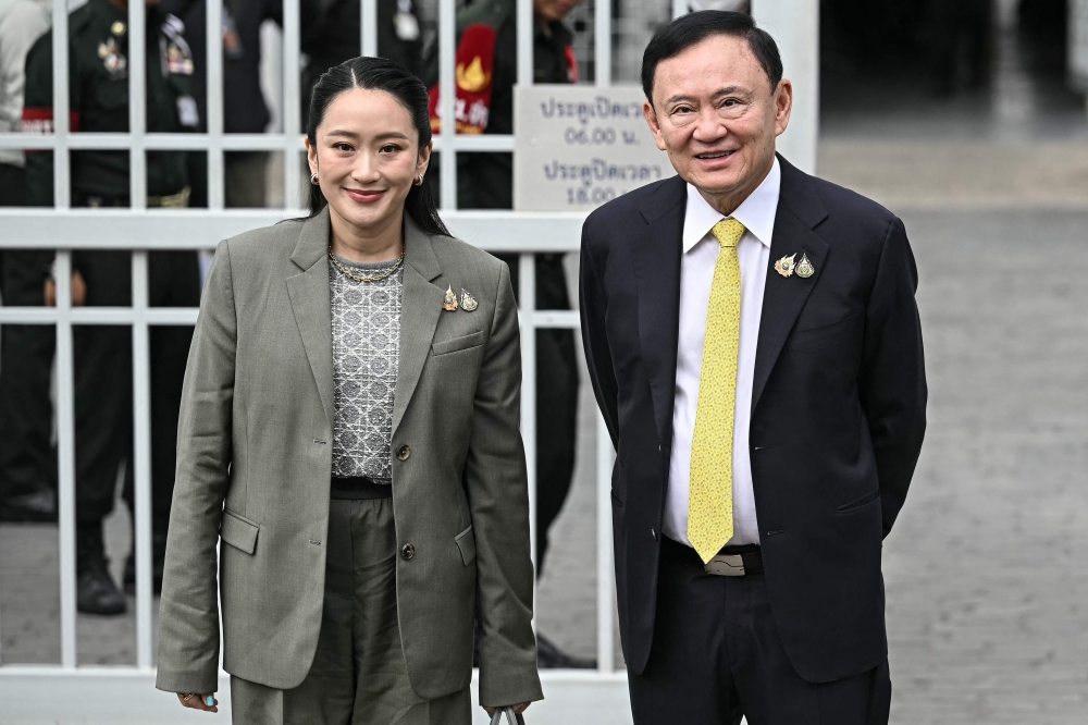 Thailand’s former prime minister Thaksin Shinawatra poses with his daughter and sacked prime minister Paetongtarn Shinawatra as they arrive at the Supreme Court in Bangkok on September 9, 2025. — AFP pic