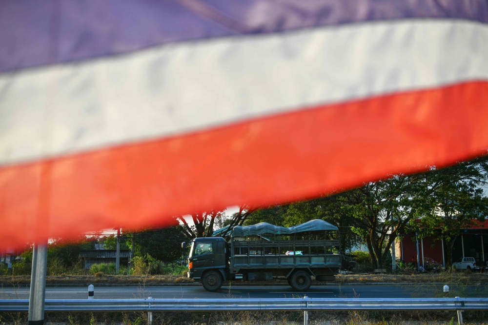 A Thai military vehicle passes by a Thai national flag in Kantharalak district in eastern Sisaket province, after weeks of deadly border clashes between the two South-east Asian neighbours Thailand and Cambodia. — AFP pic
