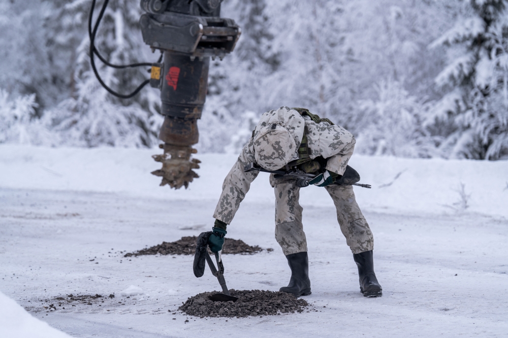 Finnish Military personnel wearing winter camouflage uniforms demonstrates the installation of land mines, as an excavator digs into the frozen asphalt to bury practice anti-tank mines that were never banned, during a media day event at the Kainuu Brigade, a Finnish Army unit in Kajaani, Finland on February 3, 2026. — AFP pic