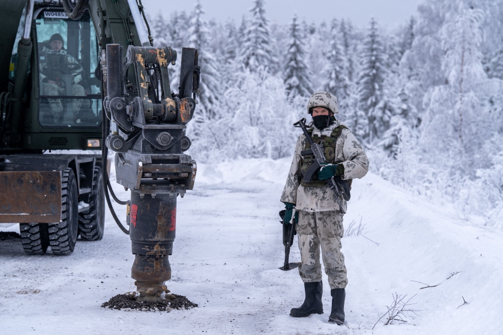 An excavator is seen next to Finnish military personnel in winter camouflage during a land mine installation demonstration at the Kainuu Brigade in Kajaani, Finland, on February 3, 2026. — AFP pic