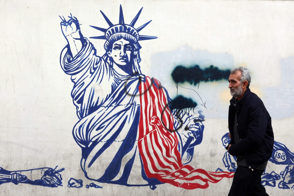 A man walks past a mural depicting the US Statue of Liberty with the torch-bearing arm broken, painted on the outer walls of the former US embassy, in Tehran on February 6, 2026. Iran’s Foreign Minister met with his Omani counterpart in Muscat on February 6, ahead of Oman-mediated talks with the US on the Islamic republic’s nuclear programme. — AFP pic