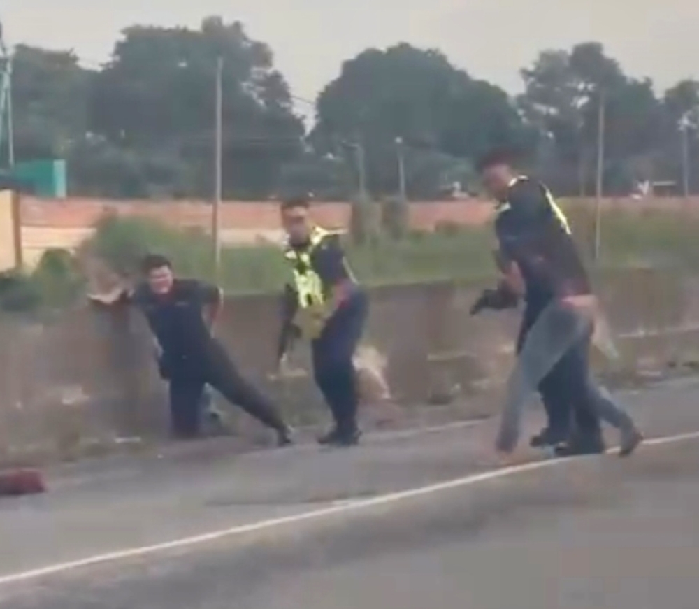 Screengrab from the viral video via Daily Express showing the police detaining the two cable car suspects on foot.