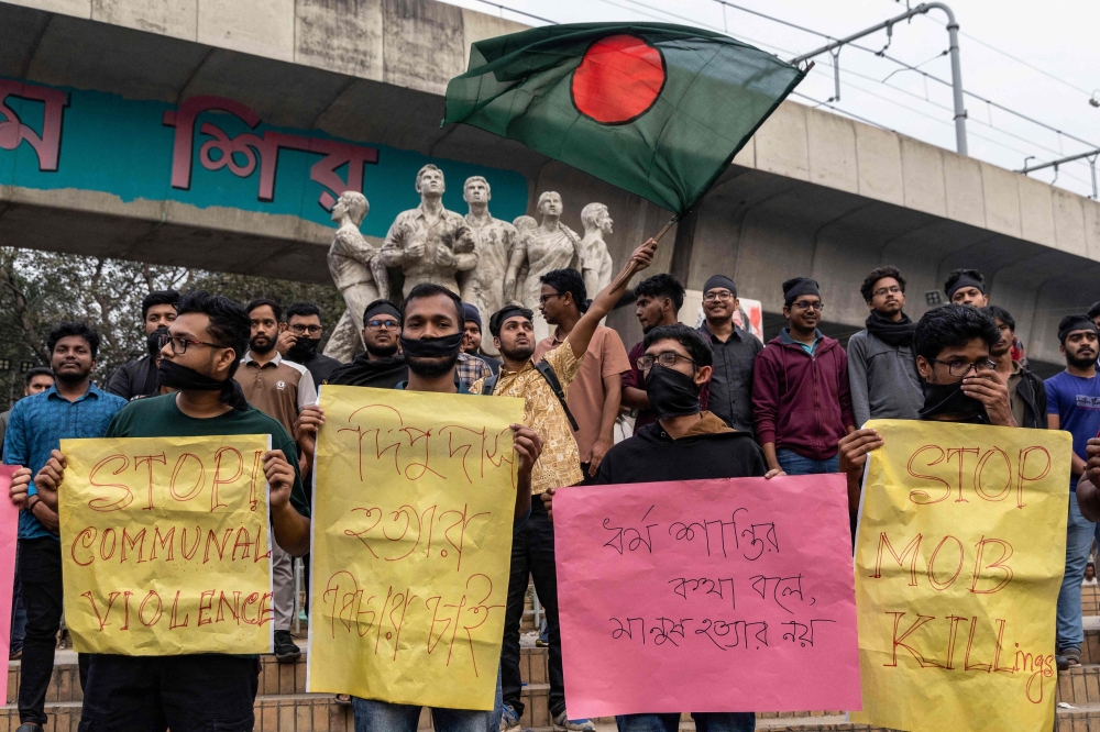 This file picture shows students with black cloth tied over their faces holding placards during a silent protest to condemn the lynching of Hindu garment worker Dipu Chandra Das near the Raju Memorial Sculpture at Dhaka University in Dhaka on December 21, 2025. — AFP pic