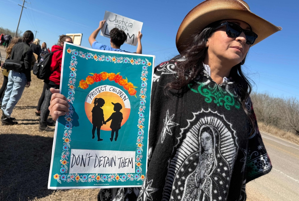 A person holds a sign calling to protect, not detain, children as people gather during a demonstration and vigil outside the South Texas Family Residential Center in Dilley, Texas, on January 28, 2026. — AFP pic