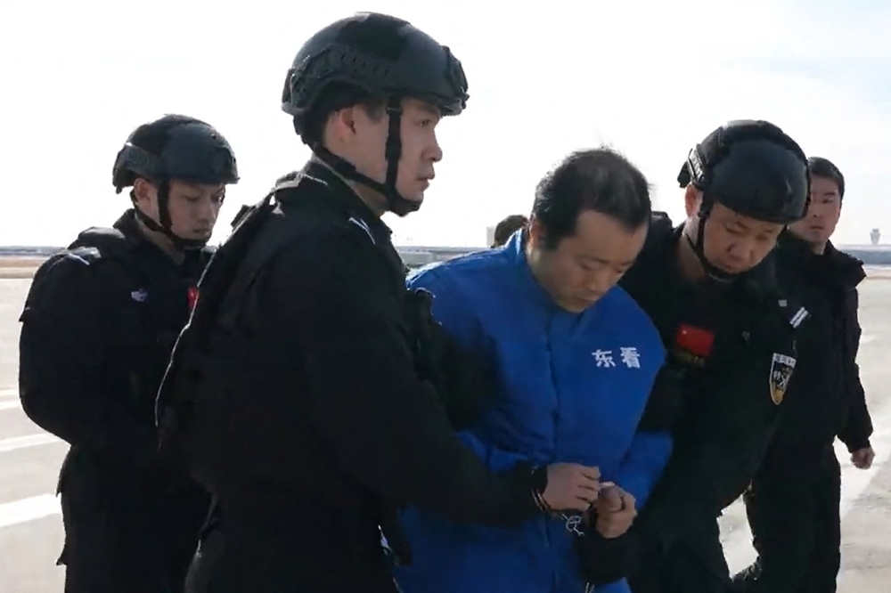 This frame grab taken from undated handout video footage released by China’s Ministry of Public Security on January 8, 2026 shows guards escorting alleged scam boss Chen Zhi (centre) off a China Southern plane in Beijing. Chen has been extradited to China from Cambodia, Beijing confirmed on January 8, after he was indicted by the United States over alleged multibillion-dollar fraud. — AFP pic/China’s Ministry of Public Security handout