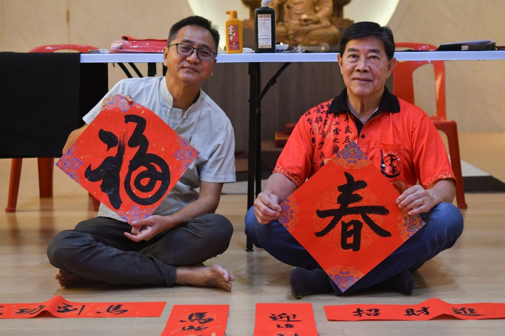Kelantan Calligraphy Association treasurer Yeap Keng Hwa (left) and committee member Yeoh Eng Chew (right) show the Chinese New Year ‘chun lian’ spring couplets they wrote at Jalan Tok Hakim, Kota Bharu. — Bernama pic