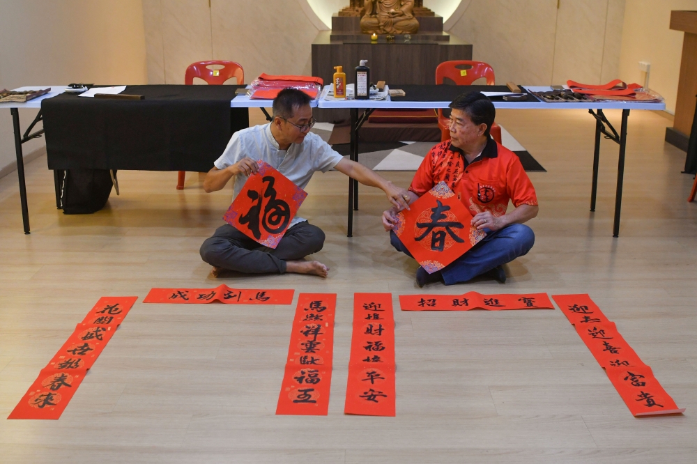 Kelantan Calligraphy Association treasurer Yeap Keng Hwa (left) and committee member Yeoh Eng Chew (right) display Chinese New Year ‘chun lian’ spring couplets at Jalan Tok Hakim, Kota Bharu. — Bernama pic