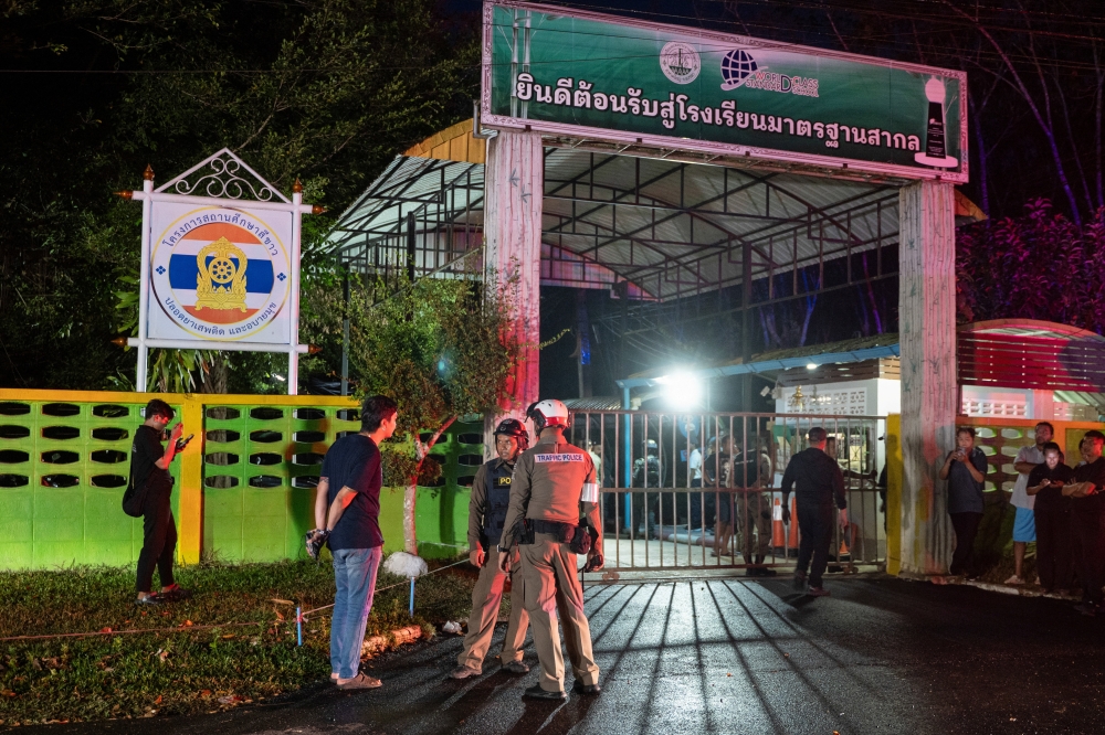Police officers and people stand near the gate of Patongprathankiriwat School, following and incident in which a gunman entered the school and held an unknown number of students and teachers hostage, in southern Thailand’s Songkhla February 11, 2026. — Reuters pic