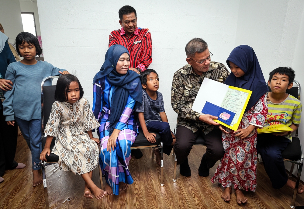 Home Minister Datuk Seri Saifuddin Nasution Ismail presents a birth certificate and MyKid to Nor Hairiza, one of five children without identification documents, as her mother Noorsyuhada Mohamad looks on at Pangsapuri Rima Riang, Petaling Jaya, February 12, 2026. — Bernama pic