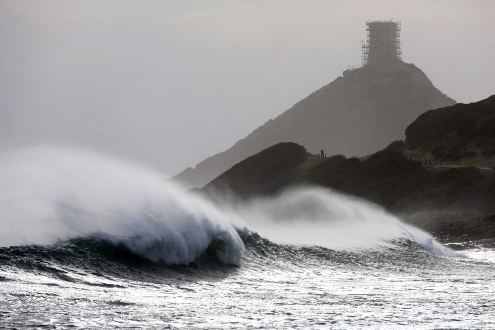 A bystander looks on as waves crash into the shore in front of The Parata Genovese Tower near Ajaccio on the French Mediterranean island of Corsica  on February 12, 2026, after winds of Storm Nils swept across France, Spain and Portugal, causing electricity outages. — AFP pic