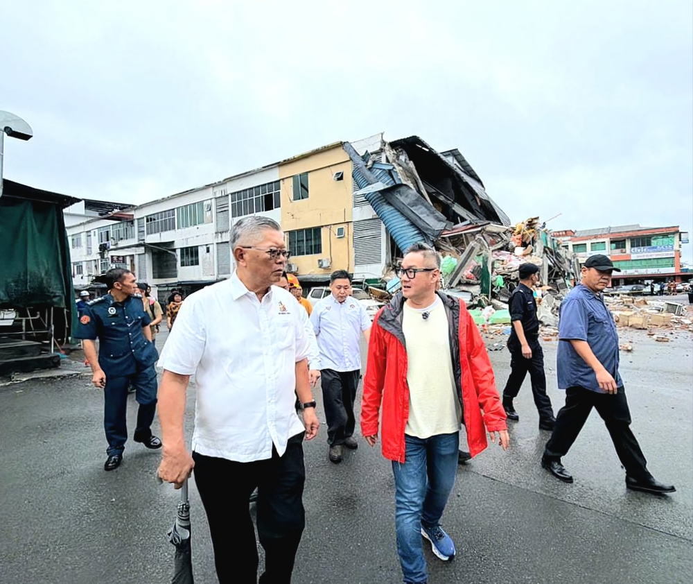 Sibu Municipal Council (MPS) chairman Clarence Ting (left) said the incident occurred at around 2.30am, leaving the structure unstable and at risk of further movement. — The Borneo Post pic