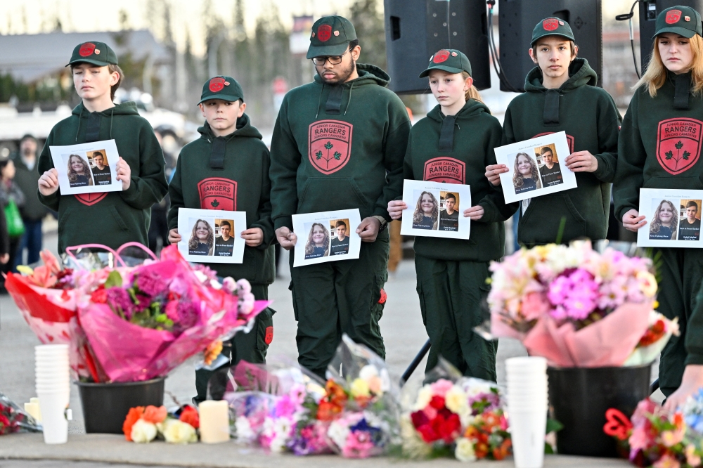 Children hold posters with the picture of the victims as they pay tribute at a makeshift memorial at the steps of the town hall, three days after one of the worst mass shootings in recent Canadian history, in the town of Tumbler Ridge, British Columbia February 13, 2026. — Reuters pic