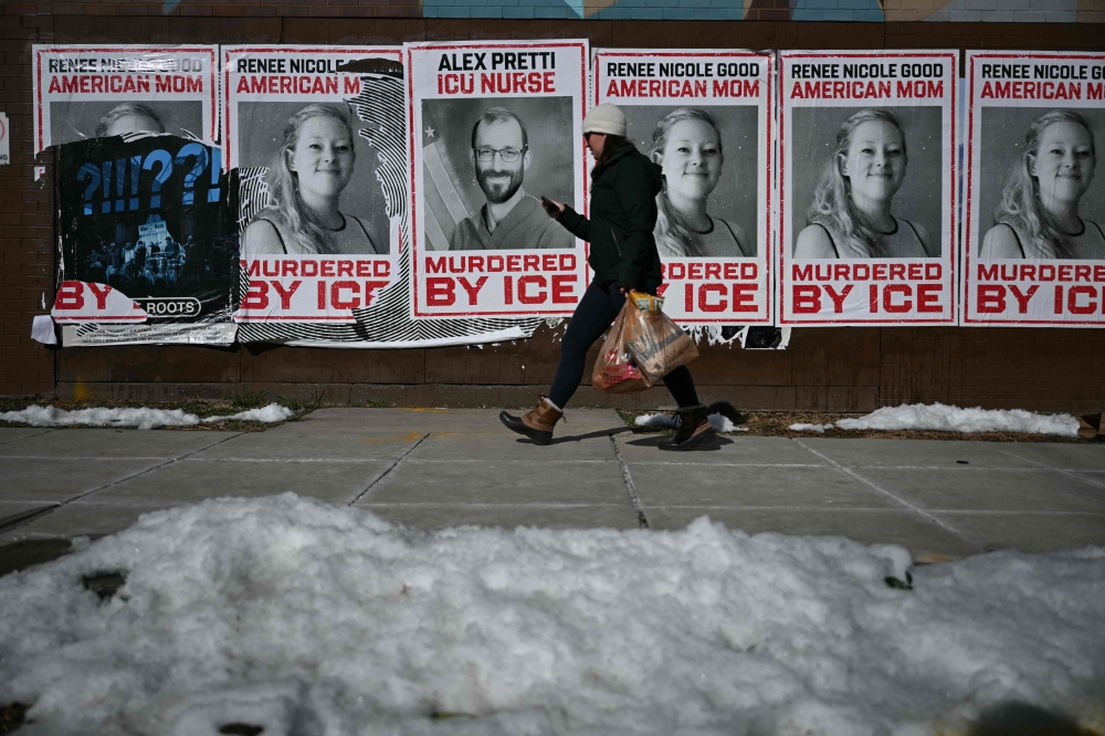 A person walks by posters on a wall showing images of Renee Good and Alex Pretti, both shot and killed by federal immigration agents, on February 9, 2026 in Washington, DC. — AFP pic 