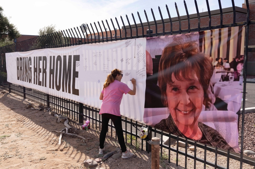 Jennifer Bond signs a banner that reads ‘Bring her home’ and shows a photo of Nancy Guthrie, US television journalist Savannah Guthrie’s abducted elderly mother, at the KVOA newsroom, where Savannah worked earlier in her career, in Tucson, Arizona February 12, 2026. — Reuters pic  