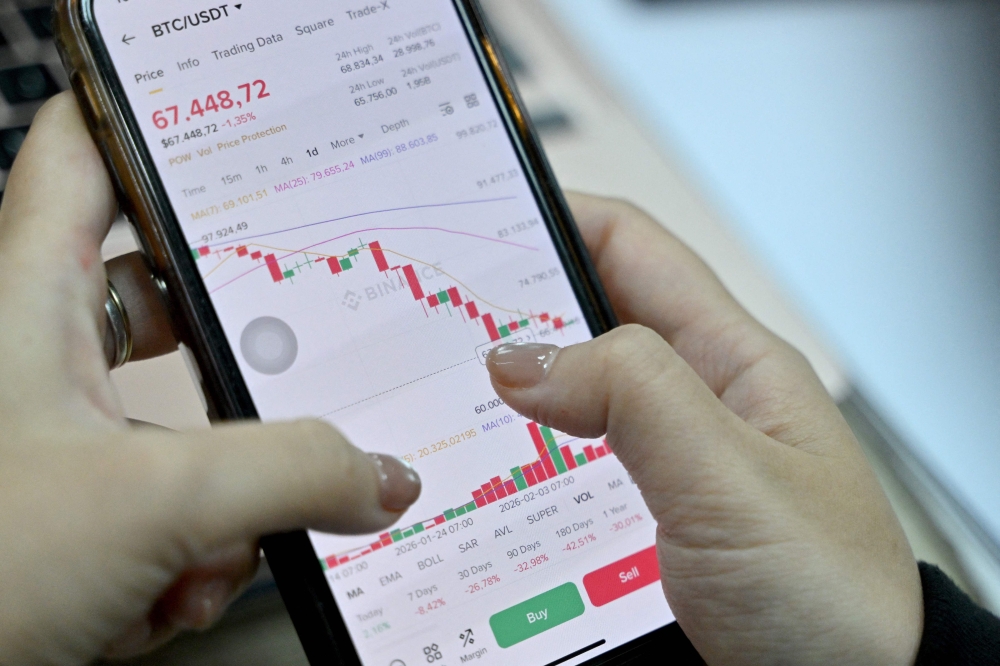 This photo taken on February 12, 2026 shows a Vietnamese cryptocurrency investor looking at the latest Bitcoin values on a smartphone in Hanoi. — AFP pic