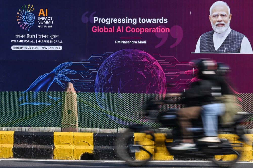 A motorcyclist rides past the hoarding of 'India AI Impact Summit 2026' along a street on the eve of the summit in New Delhi on February 15, 2026. — AFP pic