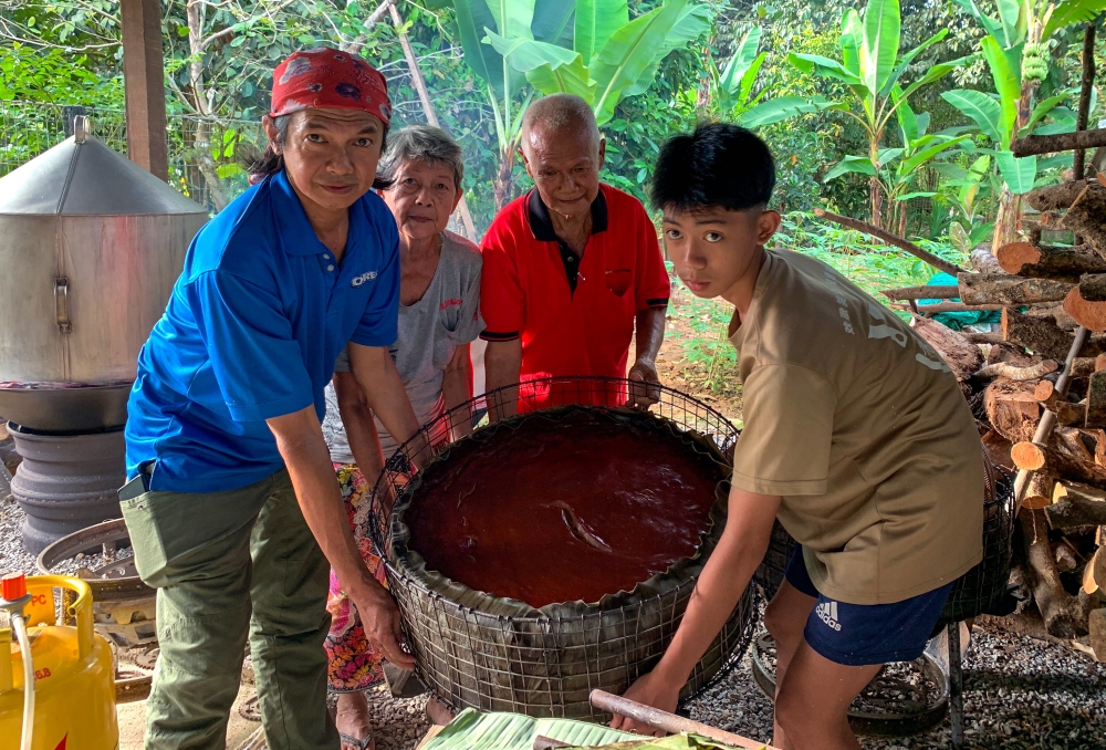 Traditional cake maker Wee Ah Liong, 80, (second from right) with his wife Ko Mek Gan, 76, (second from left), assisted by family members, lifts a cooked ‘Kiam Koay’, known as ‘Kia Koi’ in the Kelantan dialect, during a visit to Kampung Pasir Parit, Chekok recently. — Bernama pic 