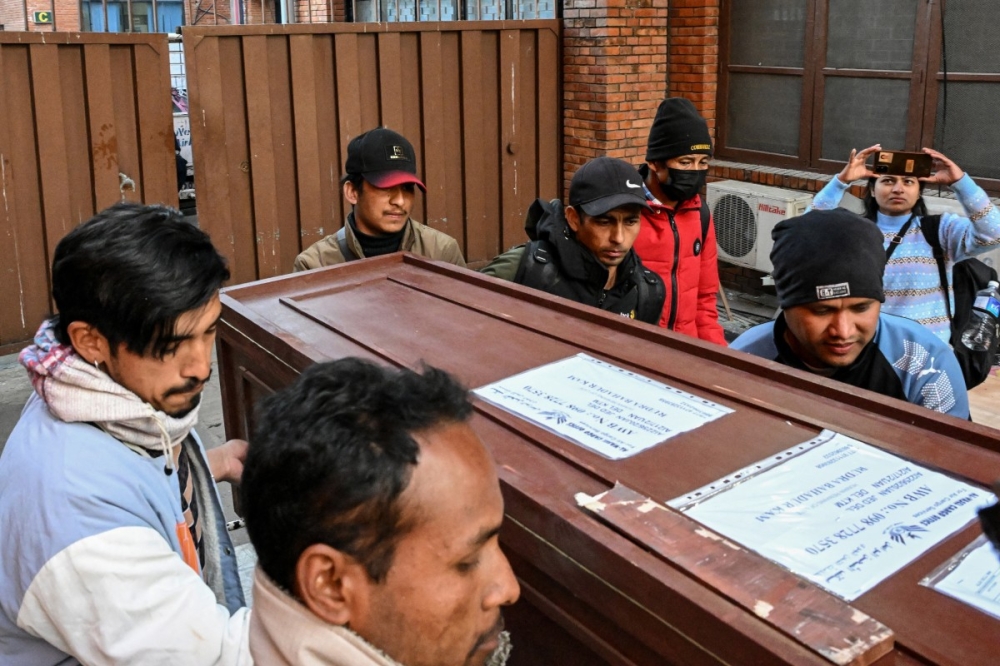 This photograph taken on January 21, 2026 shows Lalit Bishowkarma (back C), son of migrant worker Rudra Bahadur Kami, loading his father's coffin onto a truck upon its arrival at Tribhuvan International Airport in Kathmandu. — AFP pic 