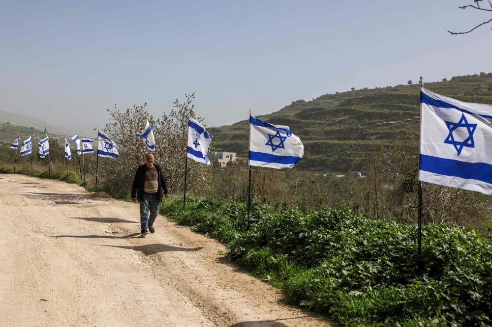 A Palestinian man from the village of Burqa, walks past a fence decorated with Israeli flags installed by Jewish settlers after they announced their control over the historical Al-Masoudiya Ottoman era train station, which operated between the Palestinian cities of Nablus and Tulkarm in the 1920s, just north of the city of Nablus, in the northern Israeli-occupied West Bank on February 15, 2026. — AFP pic 