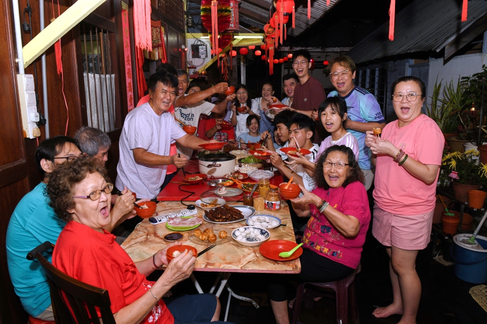 Lim Chin Hee, 71, (fourth left) serves food to his family members during a reunion dinner in conjunction with the Chinese New Year celebration at his residence at Lim Jetty, Pengkalan Weld, George Town, February 16, 2026. — Bernama pic 