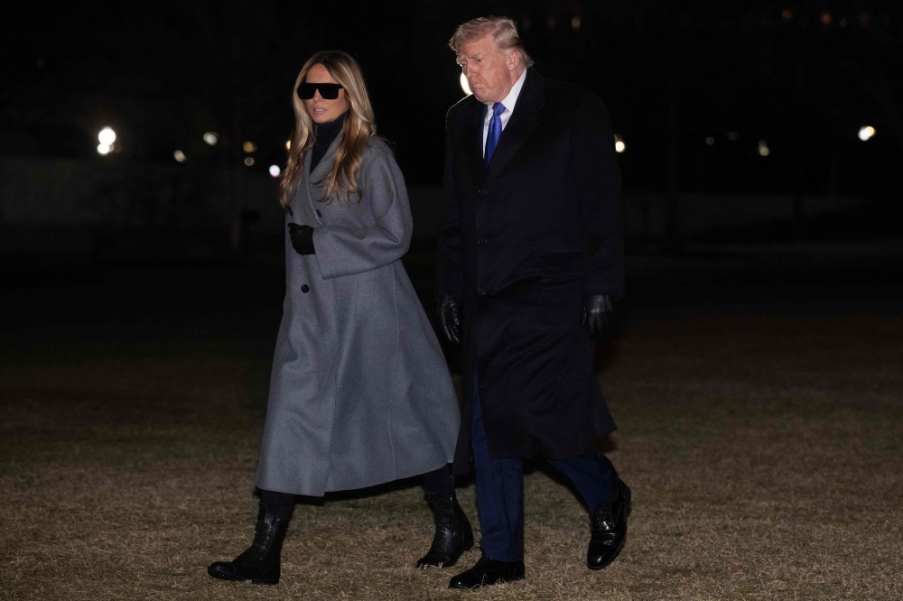 US President Donald Trump and First Lady Melania Trump walk across the South Lawn of the White House after arriving on Marine One following a weekend trip to Florida. — AFP pic