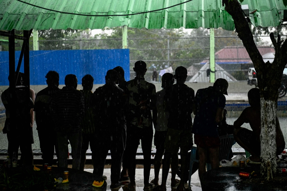 In this file photo taken on February 23, 2025, alleged scam centre workers and victims stand together during a crackdown operation by the Karen Border Guard Force (BGF) on illicit activity, at the border checkpoint with Thailand in Myanmar’s eastern Myawaddy township. — AFP pic