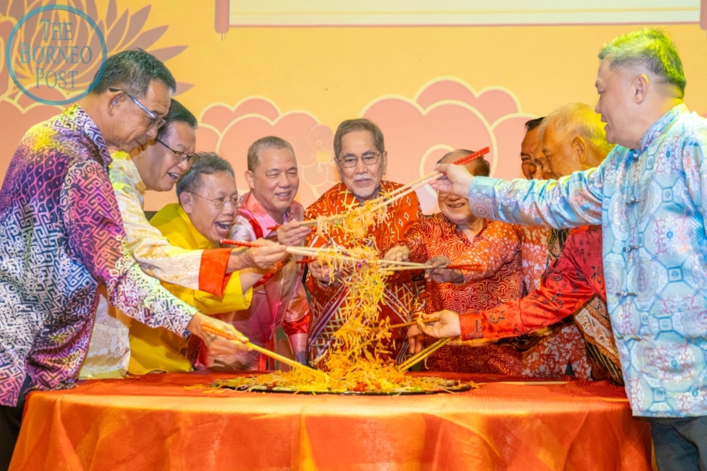 (From left) Abdul Karim, Lee, Dr Sim, Fadillah, Wan Junaidi, Uggah and others tossing the yee sang during the state-level Chinese New Year Open House in Kuching on Tuesday. — The Borneo Post pic 