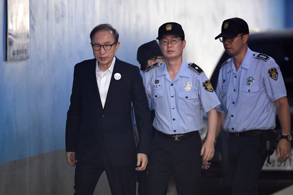This file photo taken on September 6, 2018 shows former South Korean president Lee Myung-bak (left) arriving at a court to attend his trial in Seoul. ― AFP pic