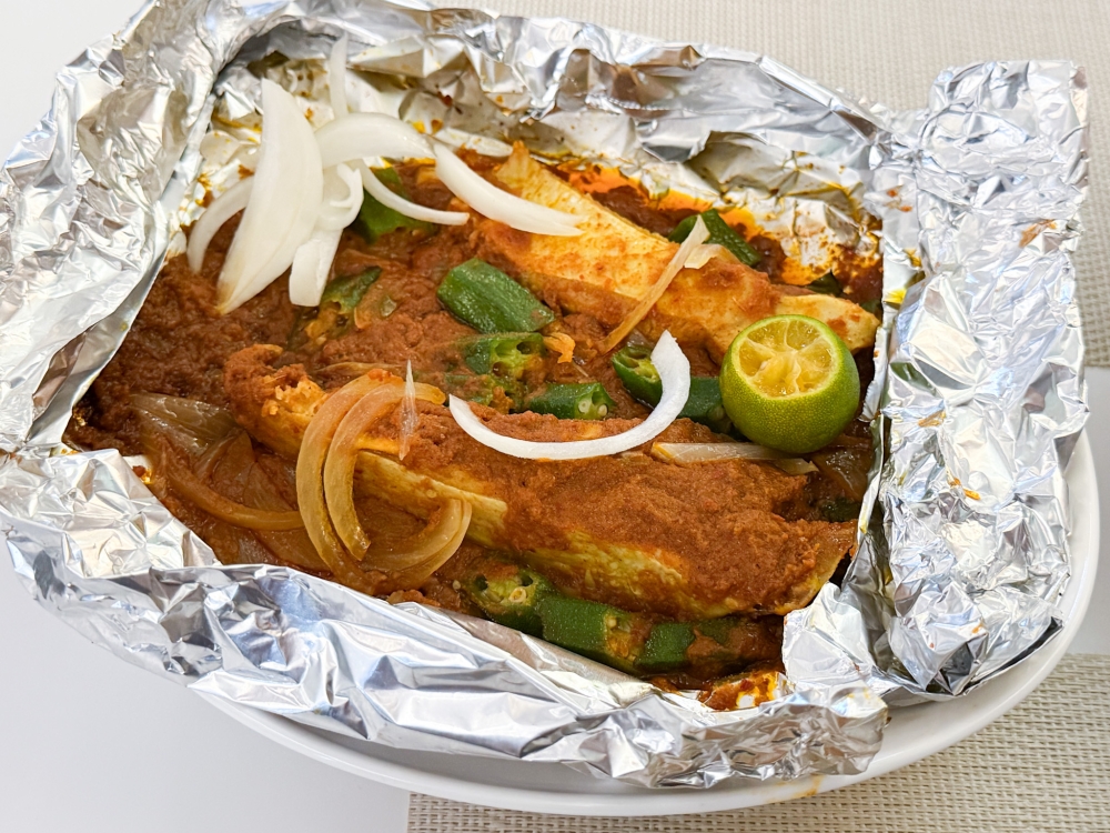 Relish the Ikan Bakar Portuguese Stingray served in a foil packet for flaky fish paired with a spicy sauce. 