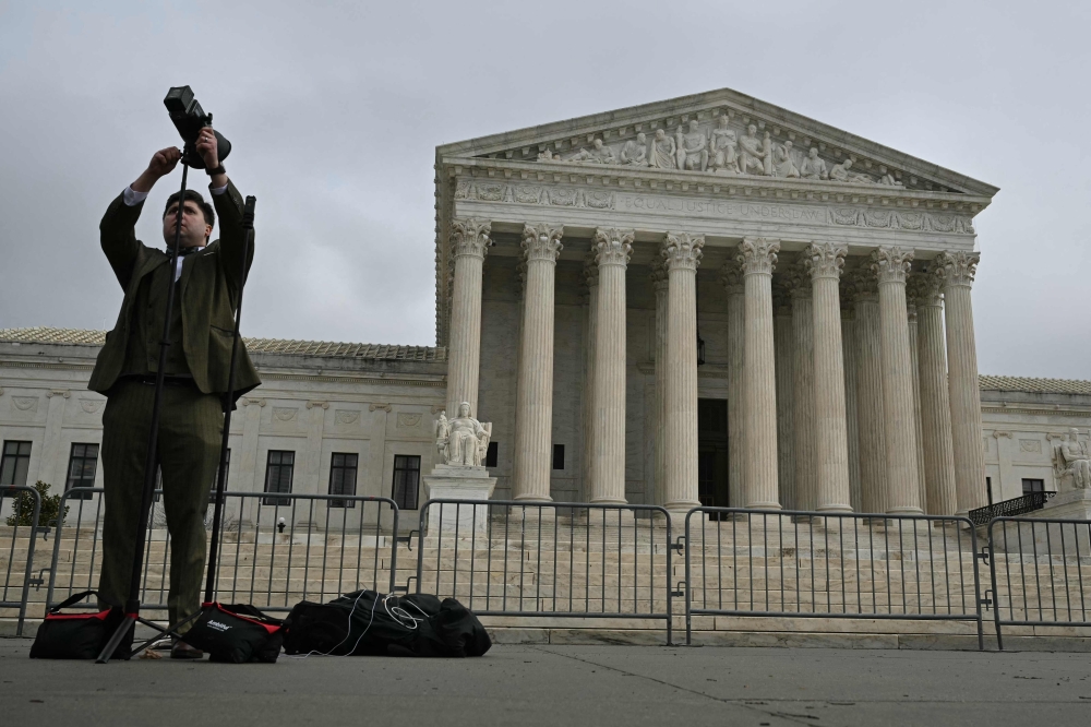 A member of the media sets his equipment in front of the US Supreme Court in Washington yesterday. — AFP pic